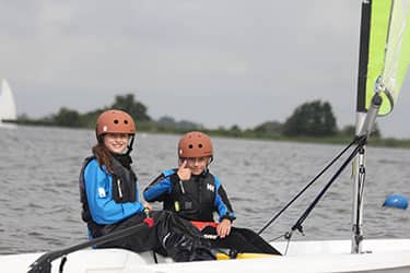 Twee meisjes zeilen samen op een zeilboot op een meer