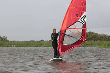 Meisje aan het windsurfen op een meer