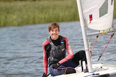 Lachende jongen genietend van een zeilboottocht op een meer