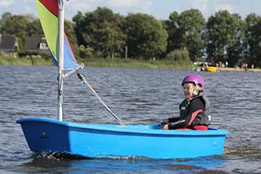 Jong meisje vaart zelfverzekerd in een boot op een rustig meer