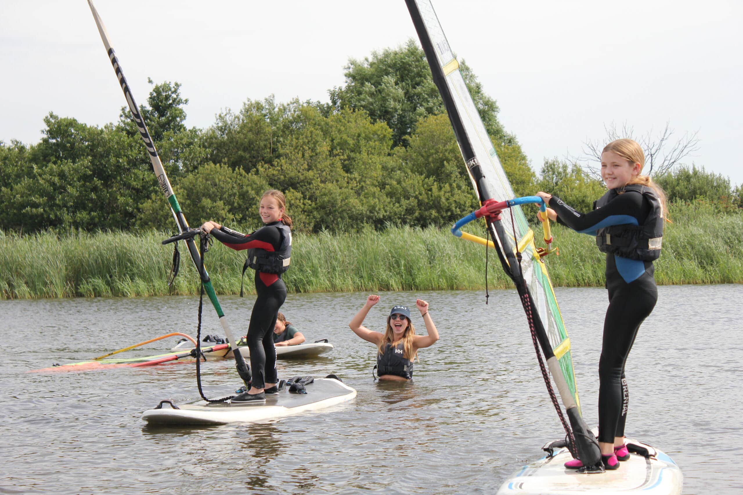 Jonge meisjes windsurfen in een meer